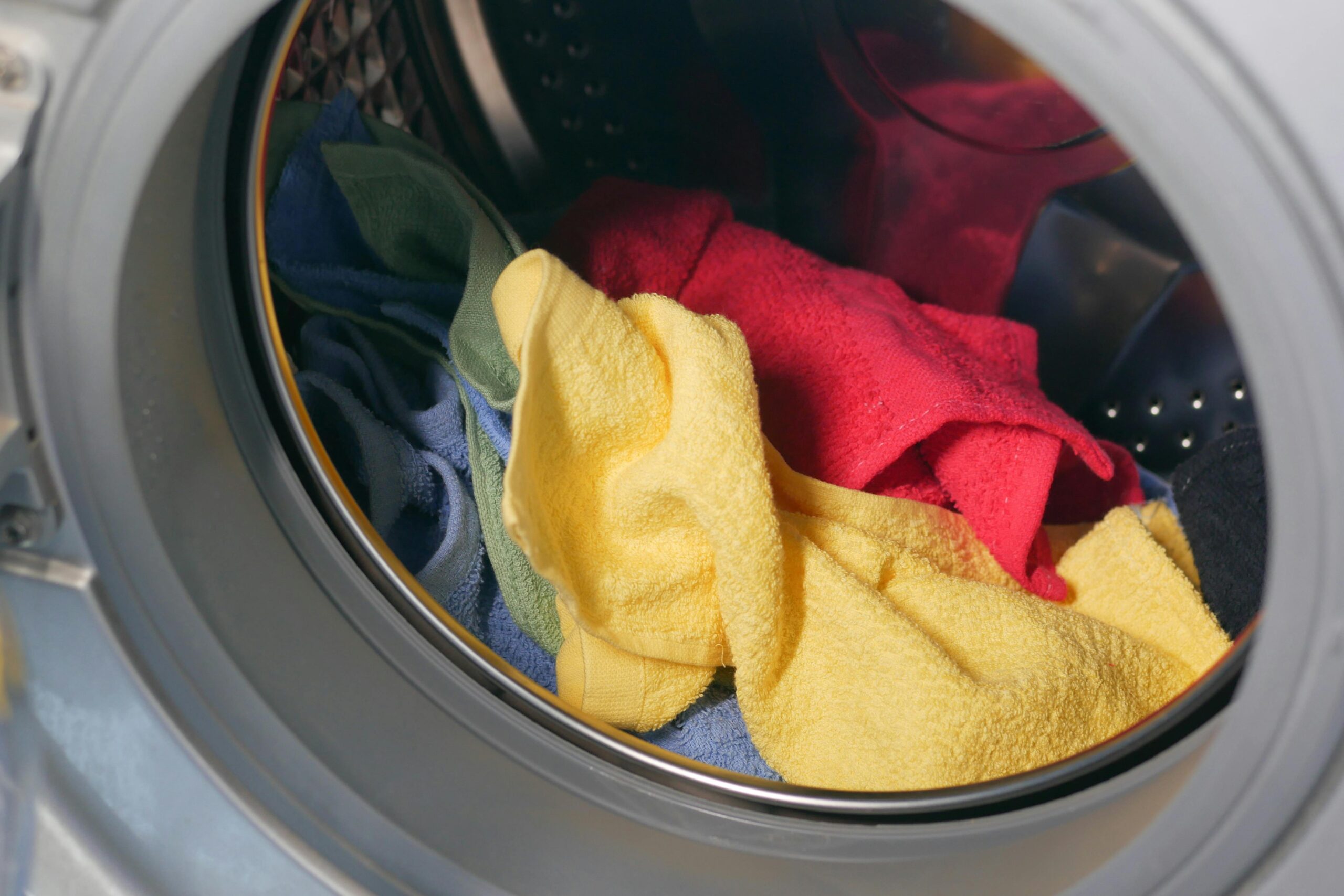 Vibrant close-up of multicolored towels inside a washing machine, ready for a wash.